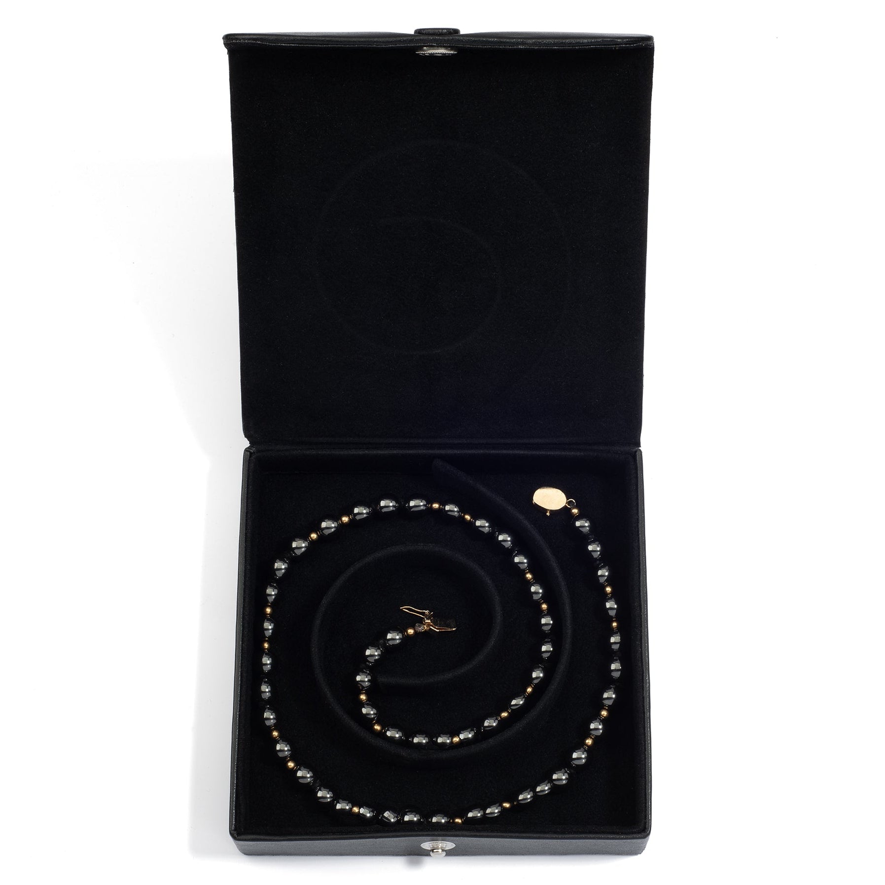An open black medium jewelry box containing a coiled pearl necklace, neatly arranged in the spiral groove.
