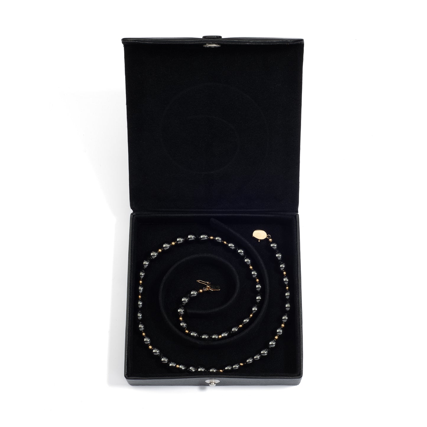 An open black medium jewelry box containing a coiled pearl necklace, neatly arranged in the spiral groove.