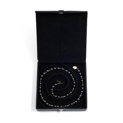 An open black medium jewelry box containing a coiled pearl necklace, neatly arranged in the spiral groove.